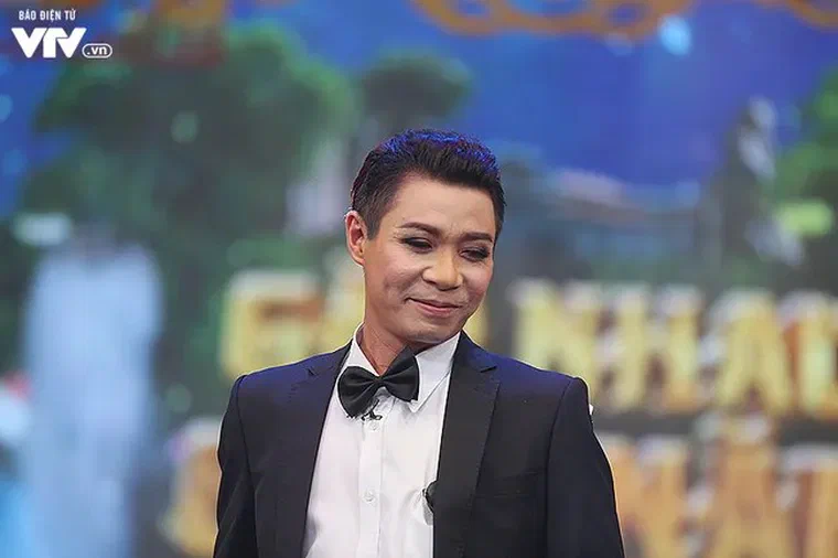 Công Lý mặc tuxedo đen, sơ mi trắng, thắt nơ đen, tóc đen ngắn hai bên gọn, phần đỉnh vuốt ngược bóng
