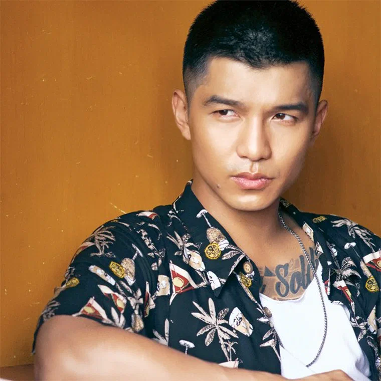 Cường Seven mặc áo hoa, tóc đen cắt rất ngắn, hai bên tỉa sát, phần đỉnh có kết cấu