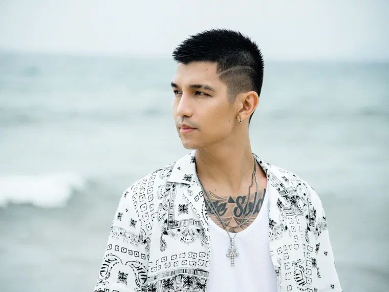 Cường Seven đứng bên bờ biển, tóc undercut hai bên cạo ngắn, phần đỉnh dài hơn và đánh rối