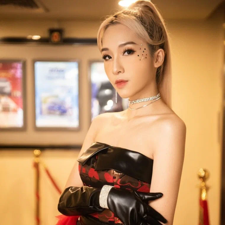 Emily với tóc nhuộm bạch kim ngả vàng, buộc thành đuôi cao, hai bên mai chải sát đầu
