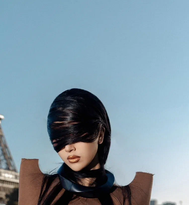 Quỳnh Anh Shyn tóc đen bóng quấn quanh đầu, che kín hai mắt, trước tháp Eiffel