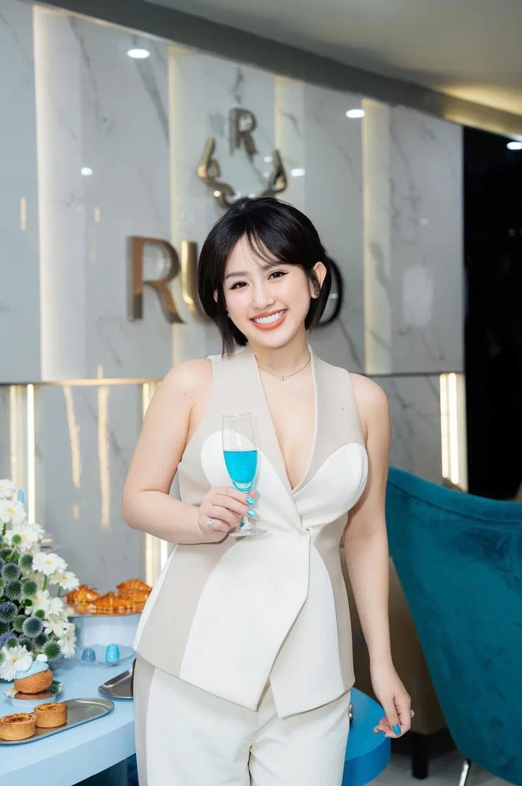 Trâm Nguyễn tóc bob đen ngắn ngang cằm, mái thưa phủ trán, ngọn ôm vào trong, áo vest trắng
