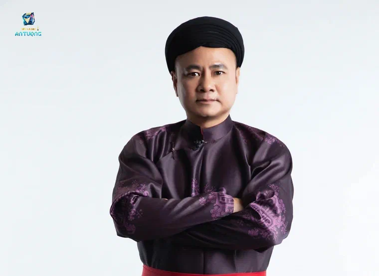Tự Long mặc áo the tím than, khoanh tay, đội khăn xếp đen che kín tóc, nền trắng