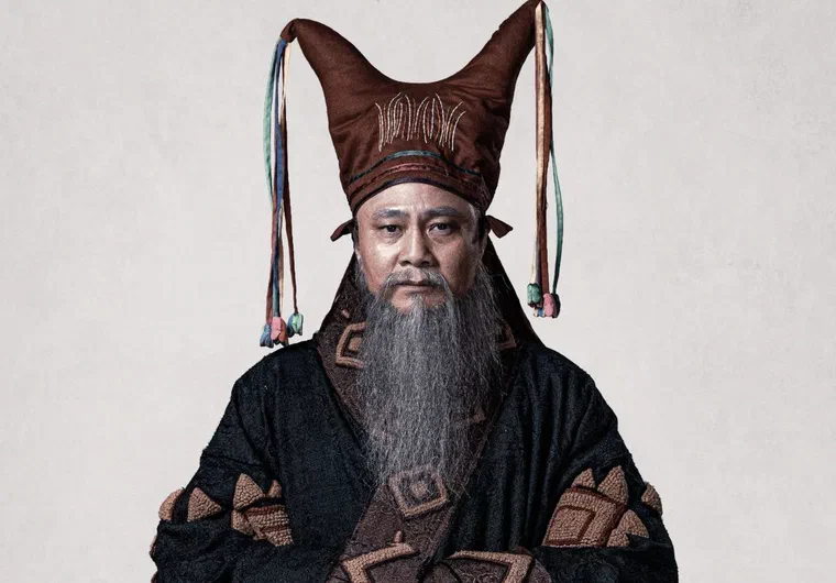 Tự Long trong vai thầy Mo người Mường, đội mũ vải nâu hai chóp nhọn rủ tua màu, râu giả bạc dài tới ngực, áo đen hoa văn